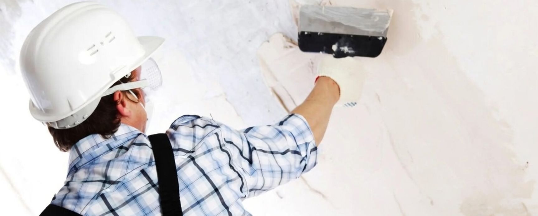 Construction worker applying gypsum plaster onto a wall surface